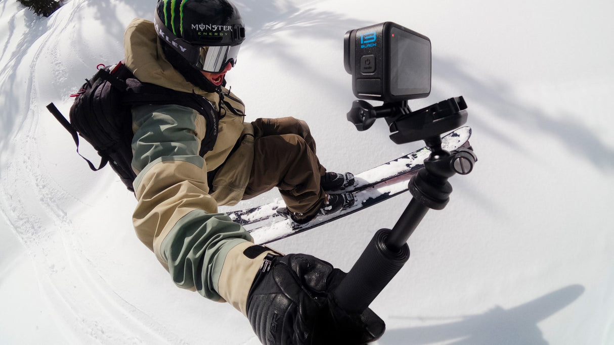 Person skiing with a GoPro camera attached to a selfie stick on a snowy slope