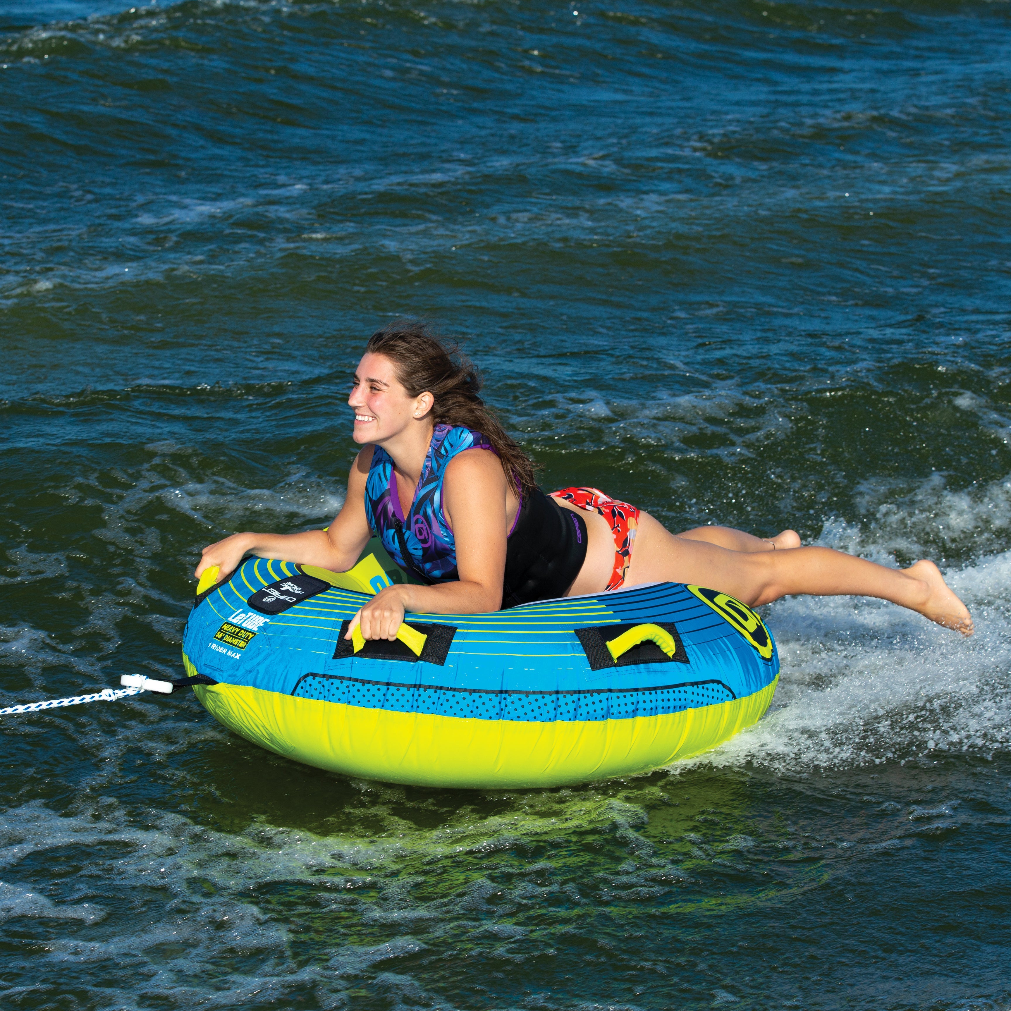 Person enjoying tubing on an OBrien LeTube Towable Tube, smiling and holding onto it.