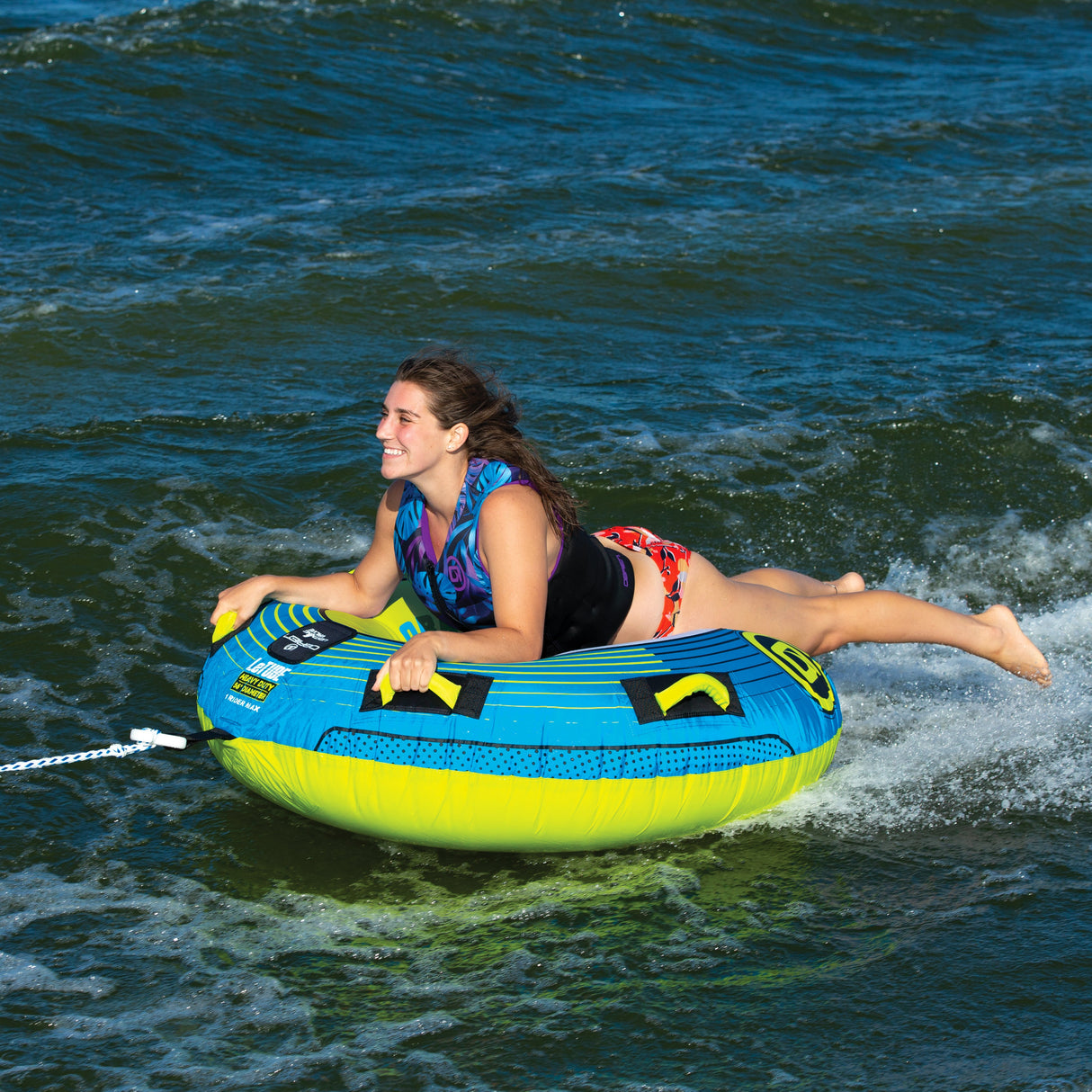 Person enjoying tubing on an OBrien LeTube Towable Tube, smiling and holding onto it.