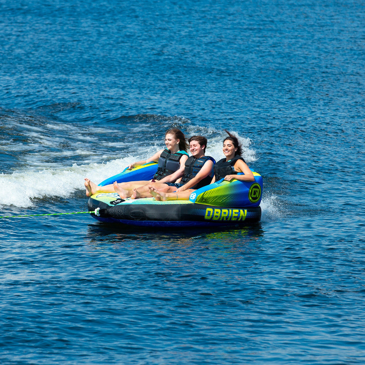 Three people towing on the OBrien Baller 3 Boat Tube, smiling in life jackets.