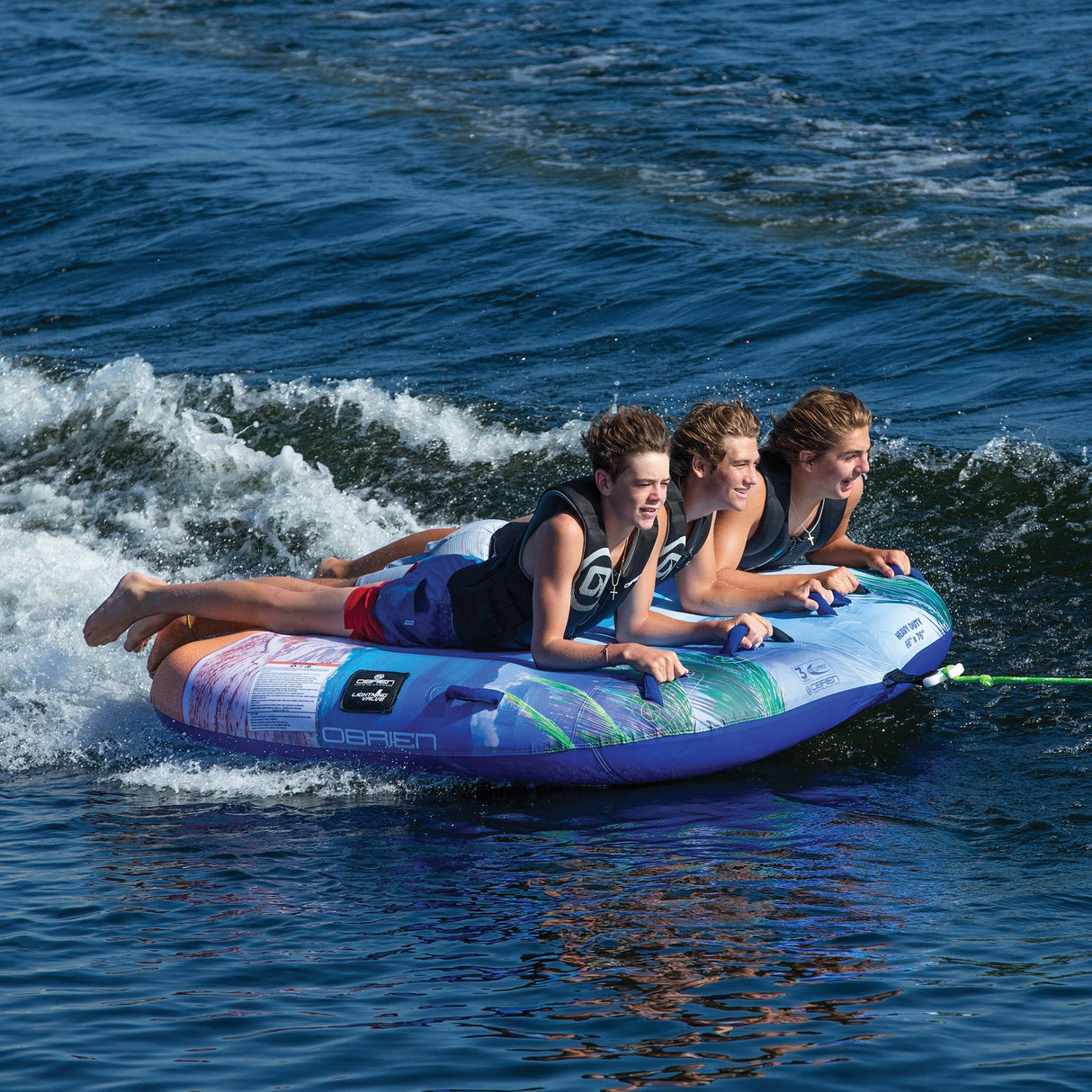 Three people smiling and enjoying a ride on the OBrien Paradise 3 Boat Tube.