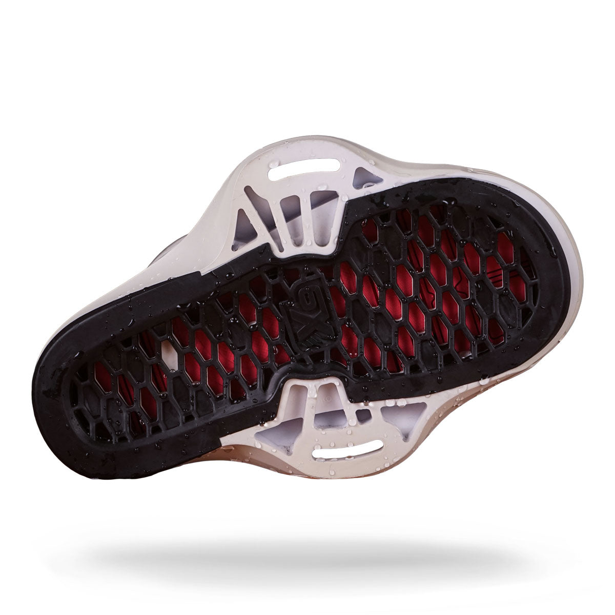Bottom view of a wakeboard binding with black, honeycomb tread. White edges with insert holes where the binding can me mounted to a wakeboard.