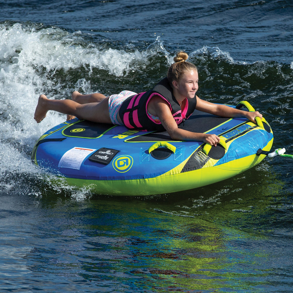 Person in a pink life jacket tubing on an OBrien Screamer Towable Tube.