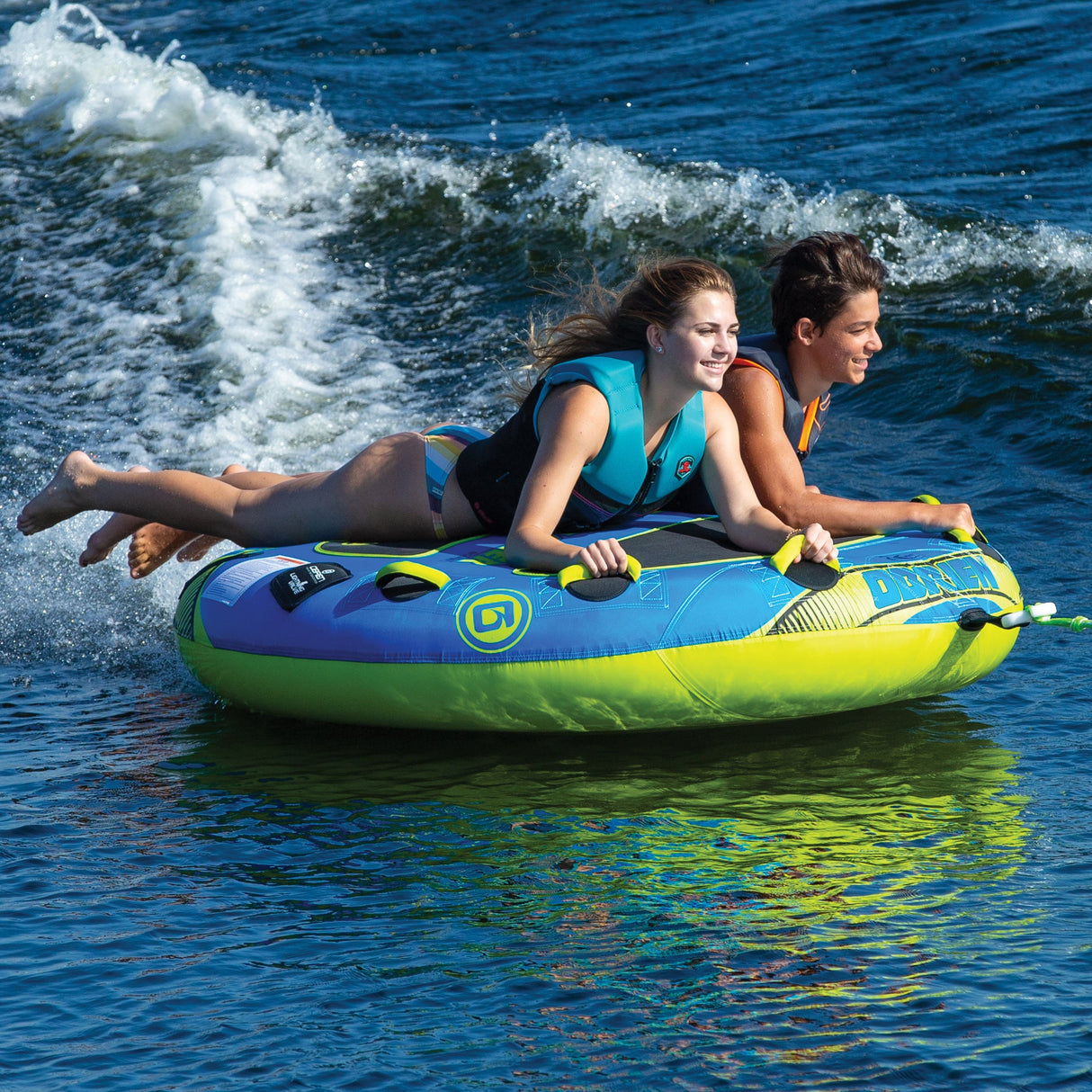 Two people smiling, having fun on an OBrien Super Screamer Boat Tube.