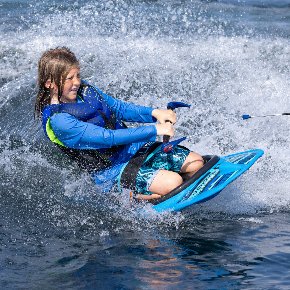 A young rider leans forward on the O'Brien Radica, extending a hand to touch the water while riding through a turn.