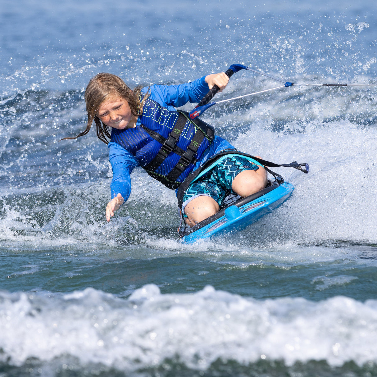 A young rider carves through the wake on the O'Brien Radica, creating a splash while holding the tow handle.