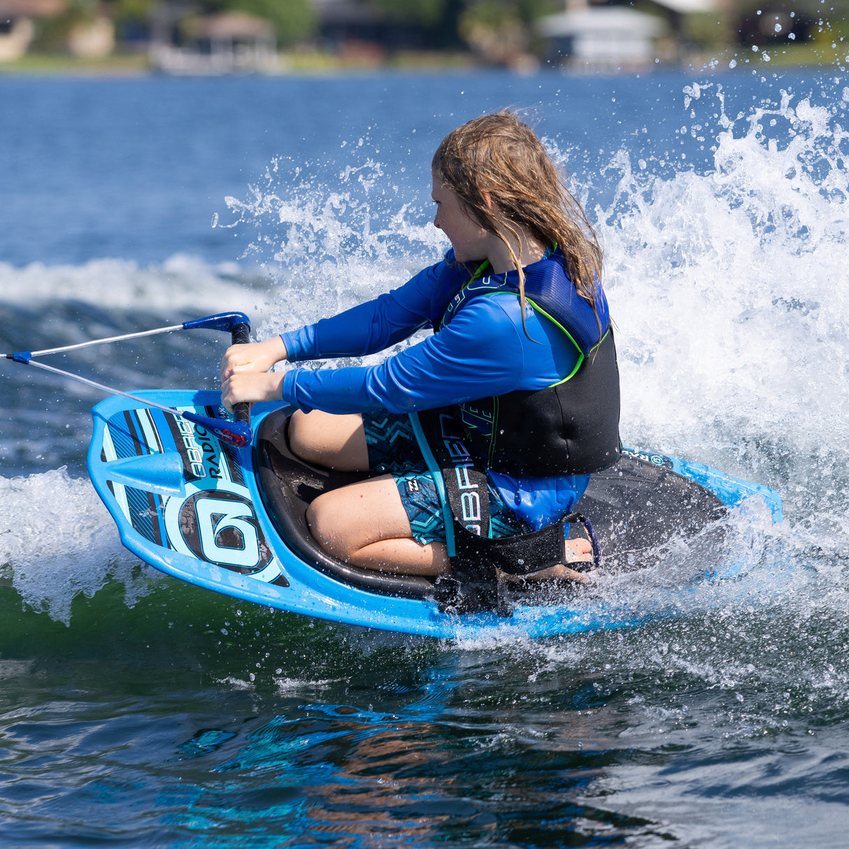 A young rider on the O'Brien Radica glides over the water, gripping the handle and balancing through a maneuver.