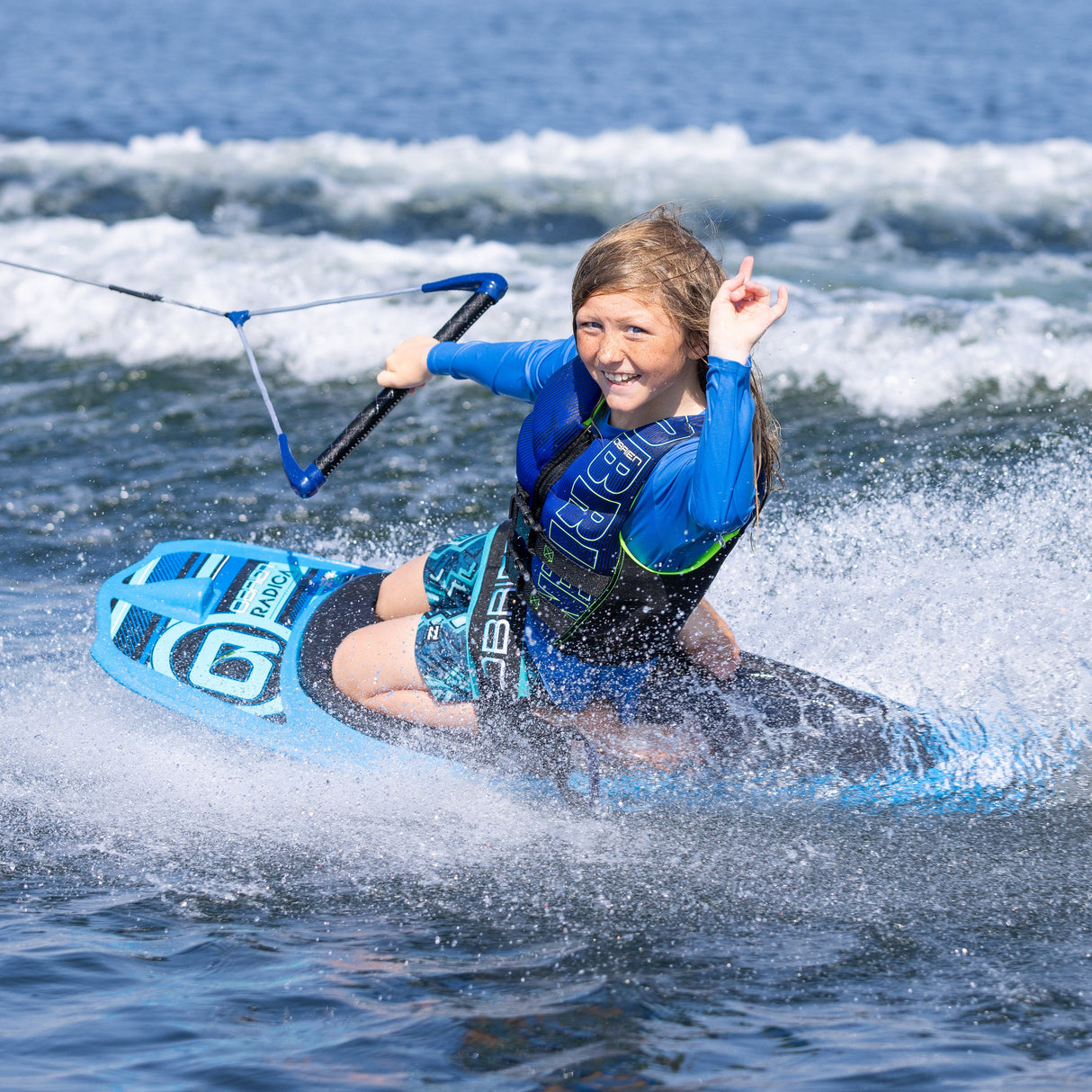 A young rider kneeboarding on the O'Brien Radica, smiling while gripping the tow handle.