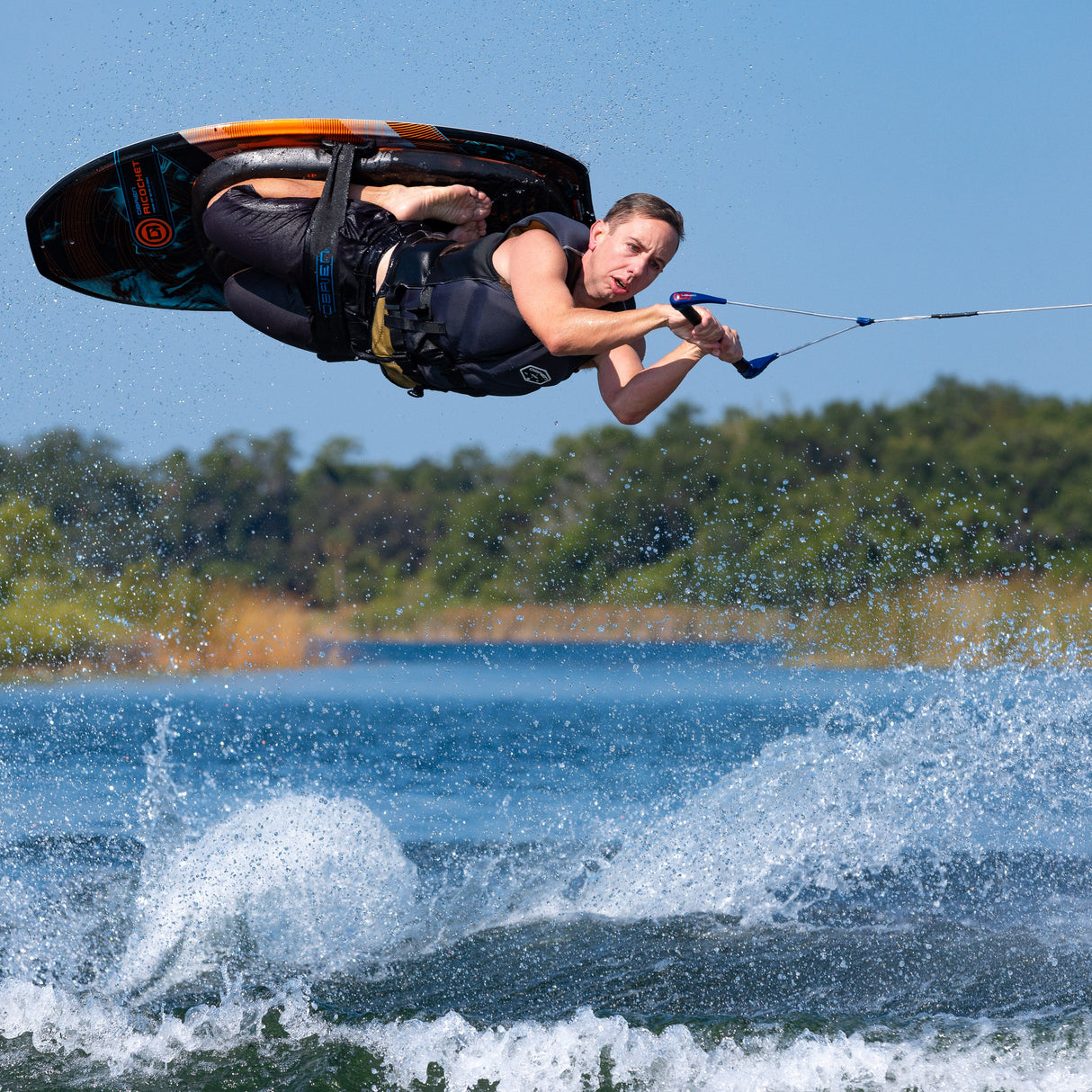 A rider performs an aerial trick on the Ricochet Kneeboard, flipping upside down while gripping the handle.