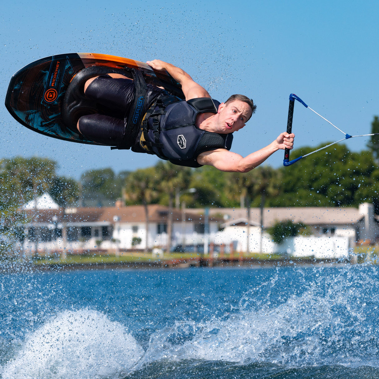 Close-up of a rider mid-air on the Ricochet Kneeboard, executing a spin while holding the tow rope.