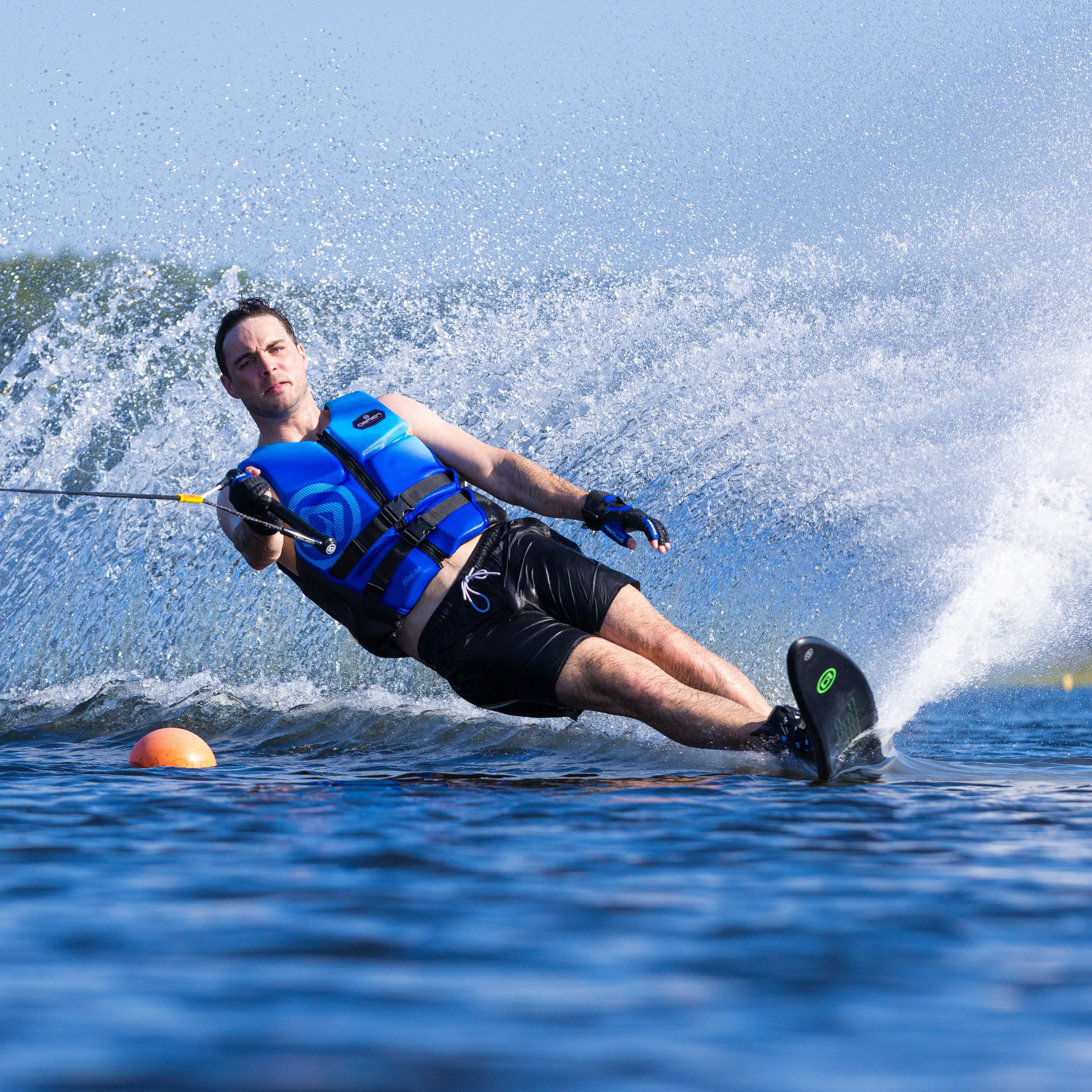 Action shot of a skier on the O'Brien Siege Slalom Waterski, carving through the water with a large spray.