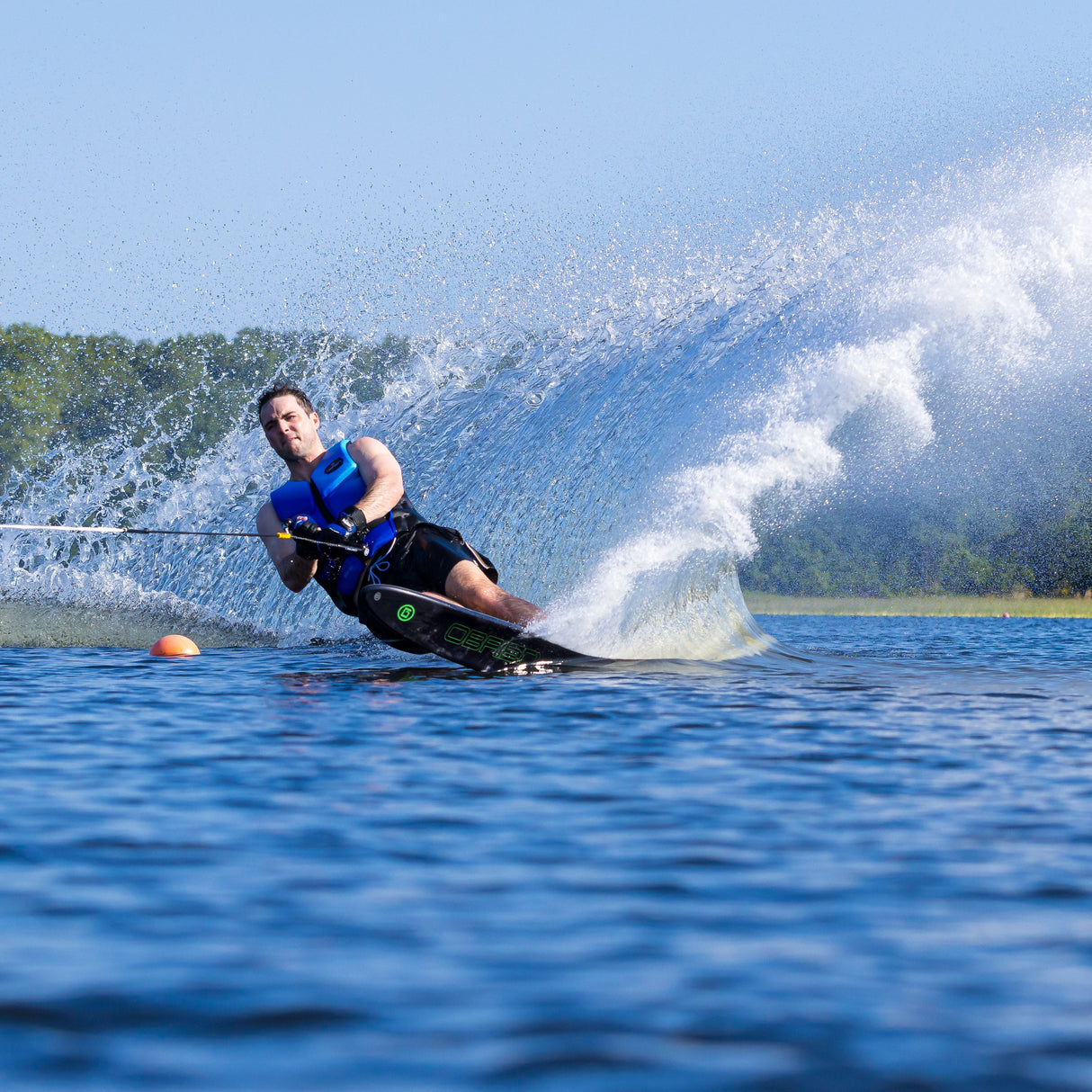 Action shot of a skier on the O'Brien Siege Slalom Waterski, carving through the water with a large spray.