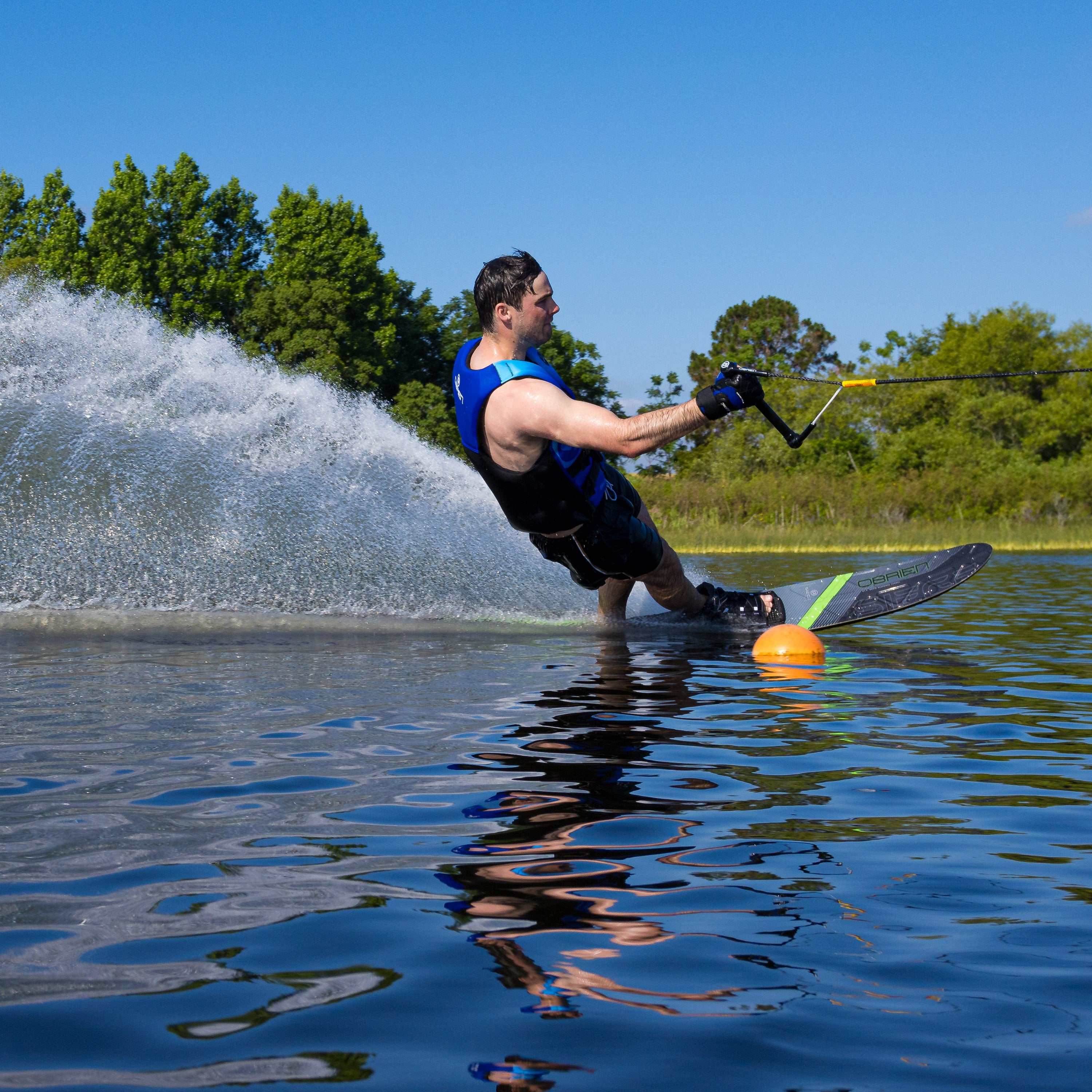 Dynamic shot of a skier leaning into a turn on the O'Brien Siege Slalom Waterski, creating a powerful spray.