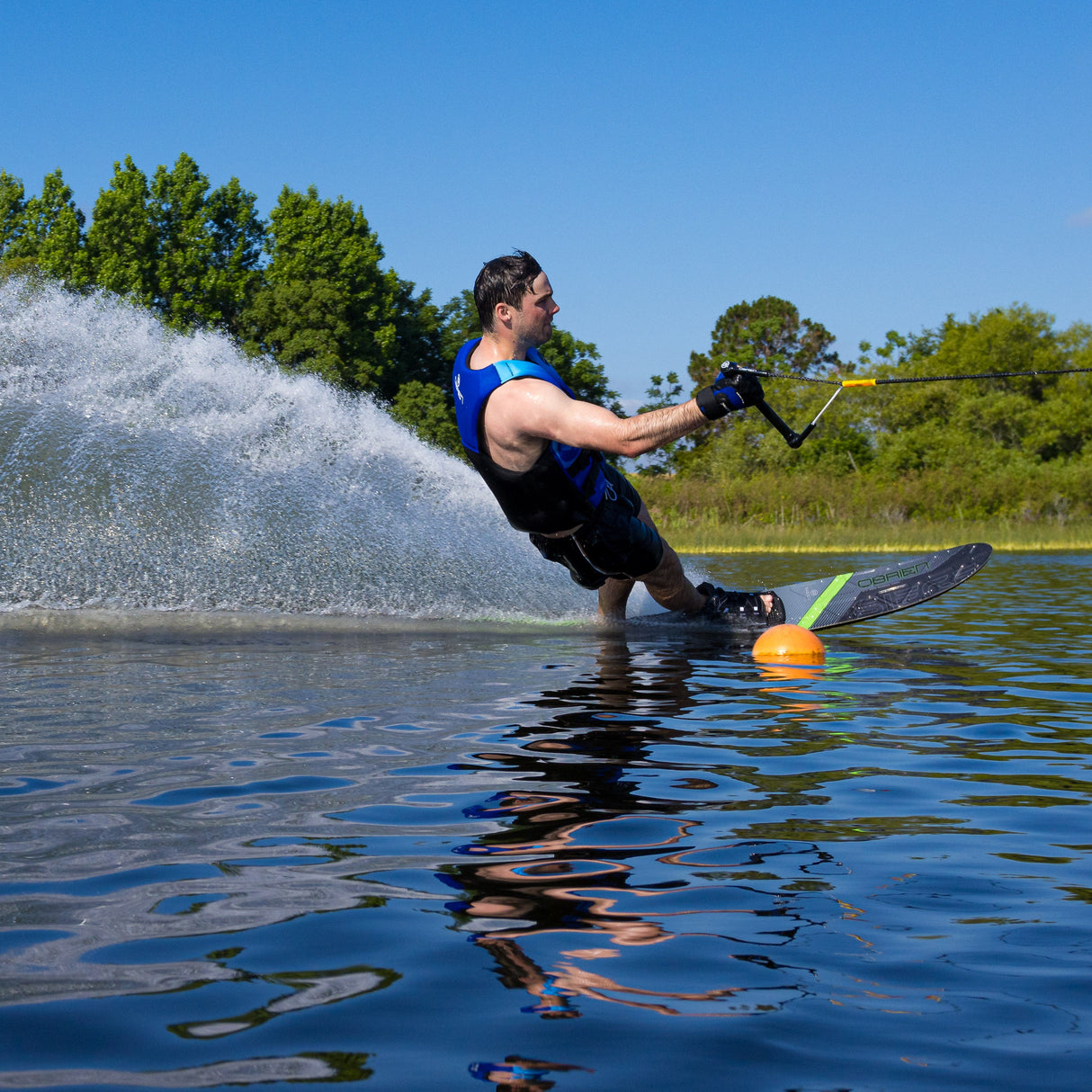Dynamic shot of a skier leaning into a turn on the O'Brien Siege Slalom Waterski, creating a powerful spray.