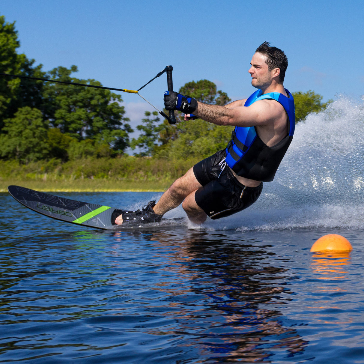 Low-angle action shot of a skier on the O'Brien Siege Slalom Waterski, highlighting speed and precision.