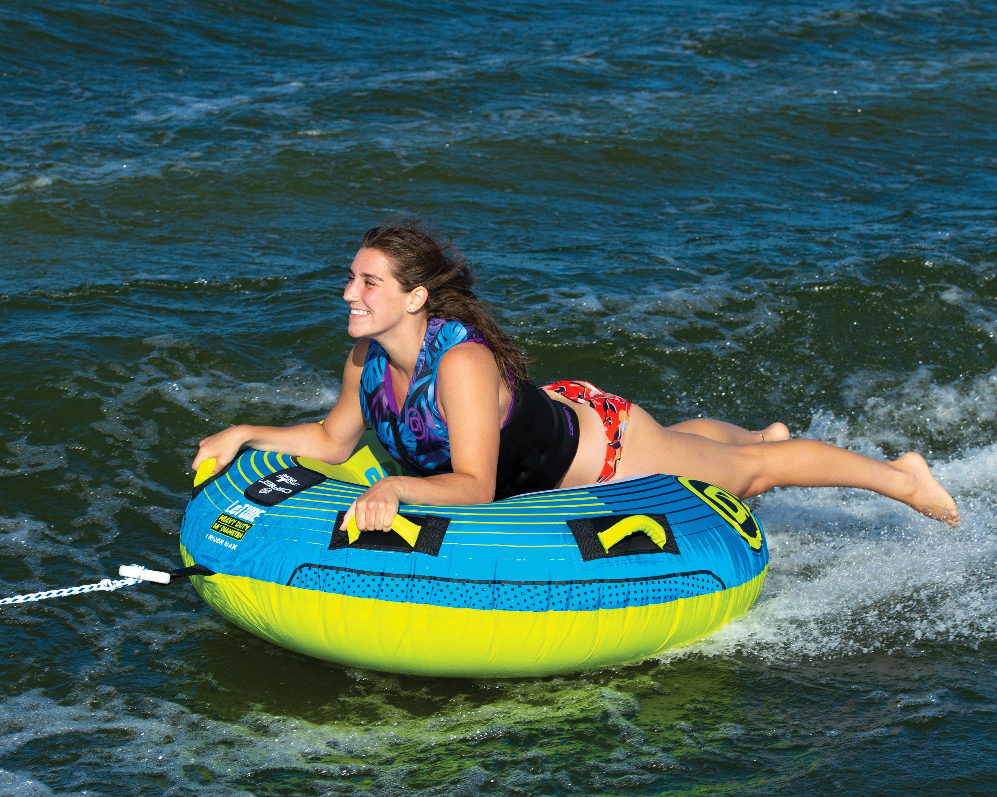 Person enjoying tubing on an OBrien LeTube Towable Tube, smiling and holding onto it.