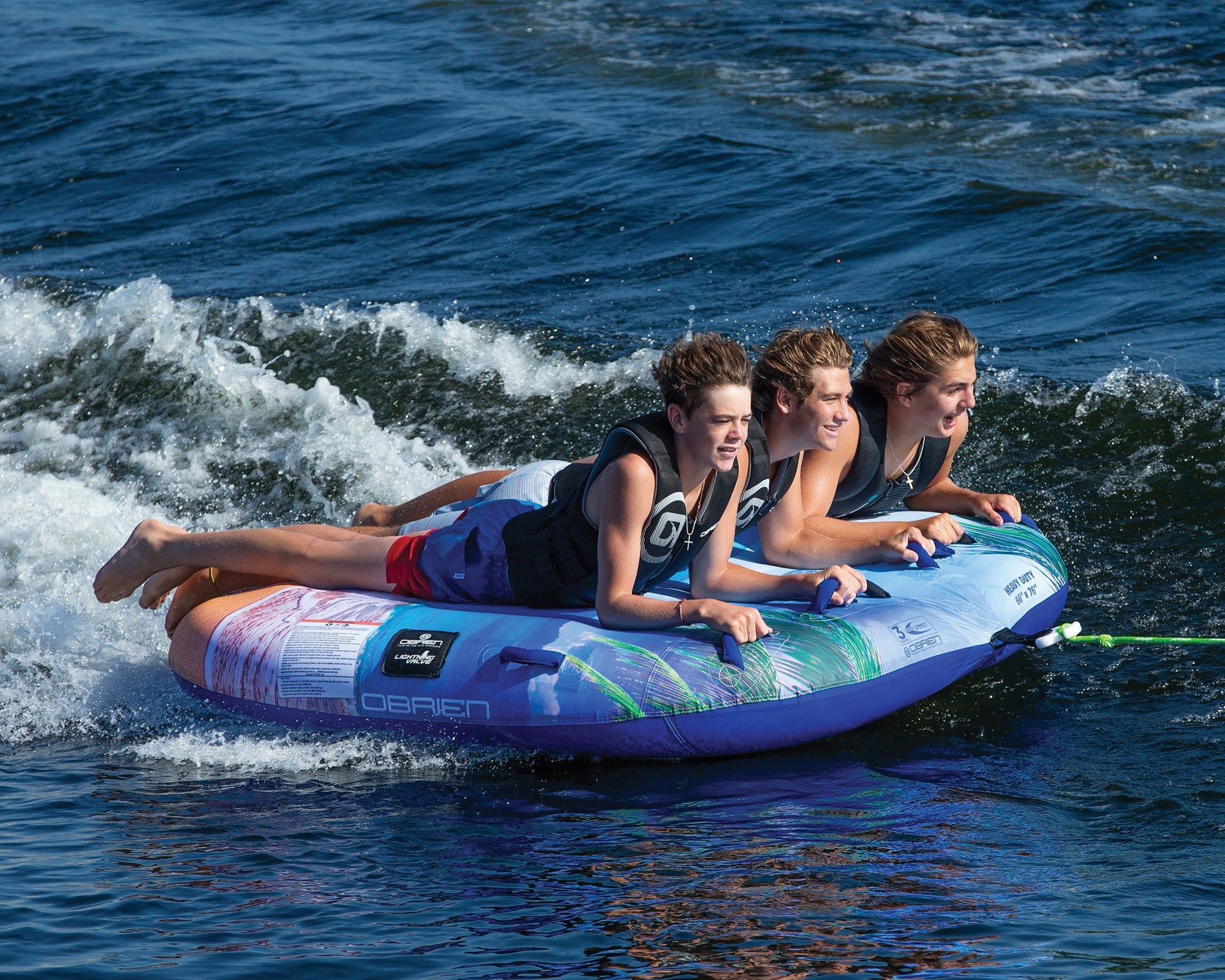 Three people smiling and enjoying a ride on the OBrien Paradise 3 Boat Tube.