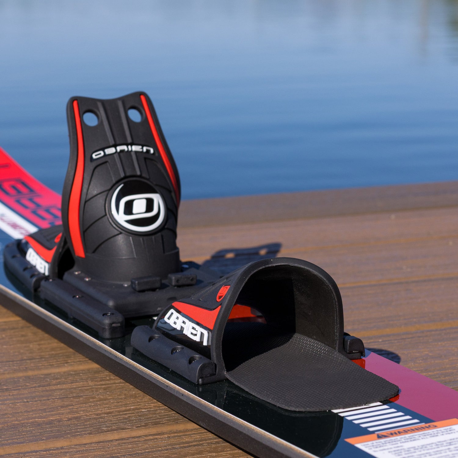 Water ski with bindings on a wooden dock by water