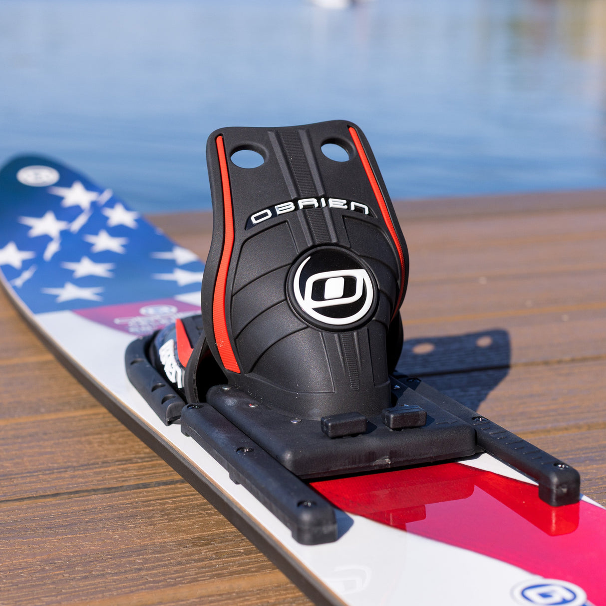 Black surfboard leash holder with 'O'Brien' branding on a water ski against a blurred water background.