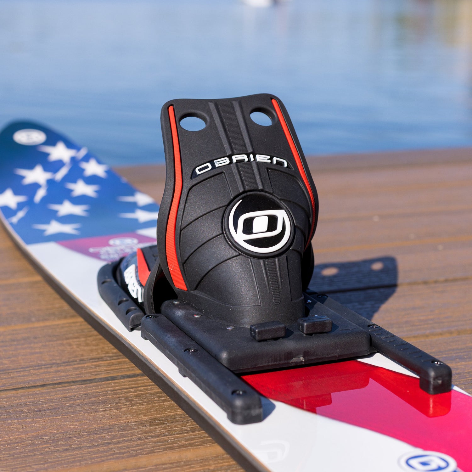 Black surfboard leash holder with 'O'Brien' branding on a water ski against a blurred water background.