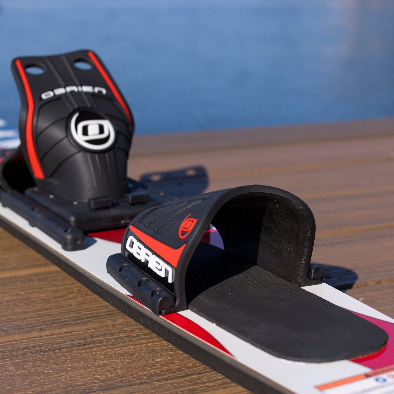 Close up of a red black and white water ski on a wooden dock.