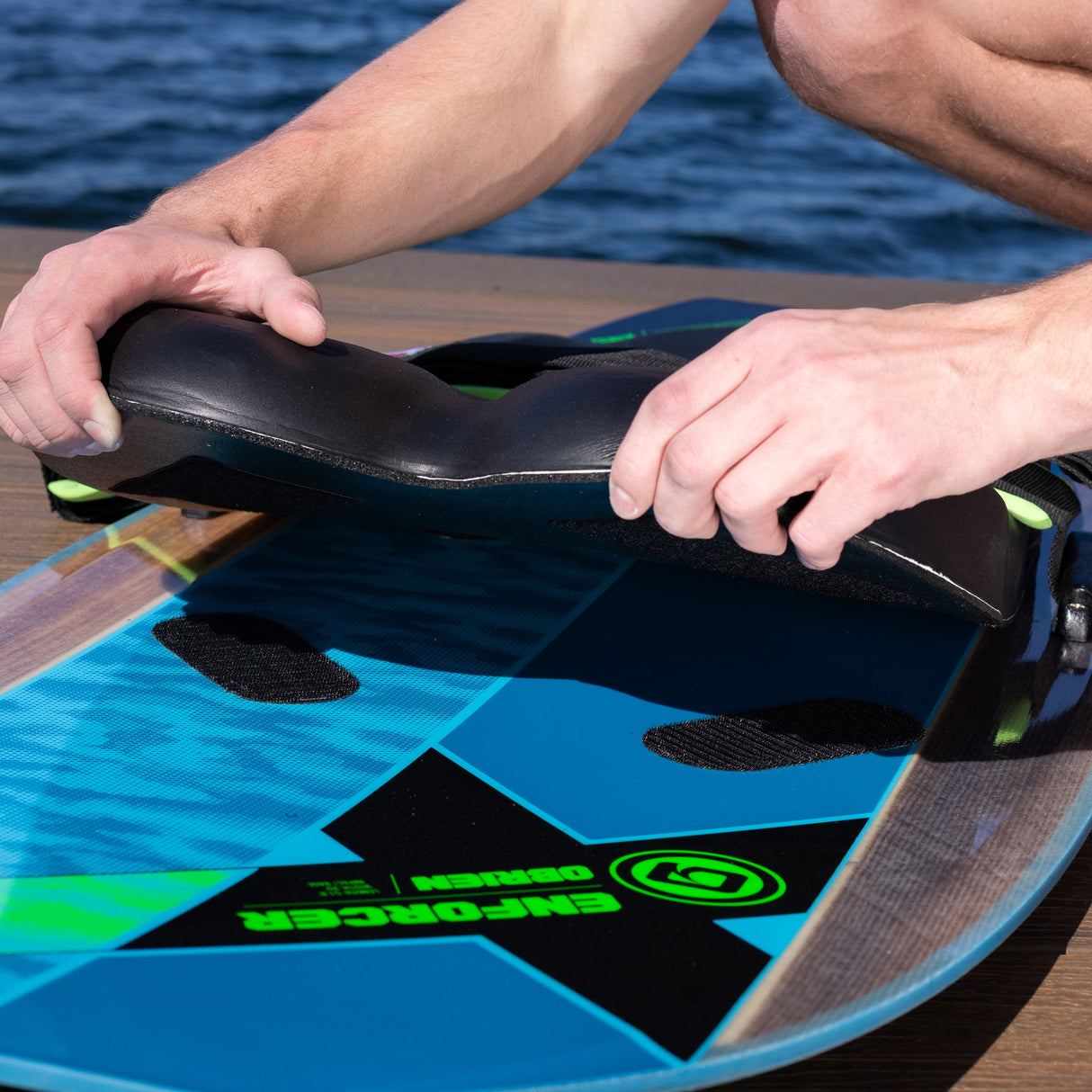 Hands lifting the removable black knee pad from the O'Brien Enforcer Kneeboard deck.